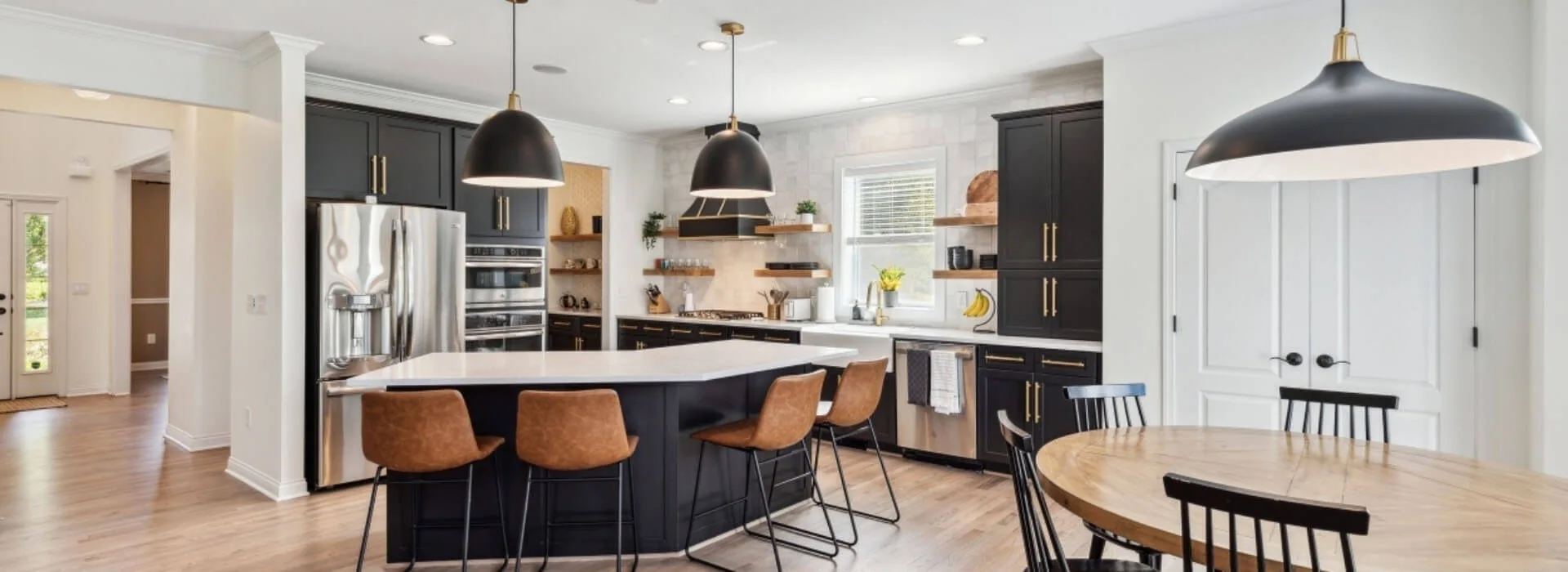 Finished kitchen with dark painted cabinets and a bright island