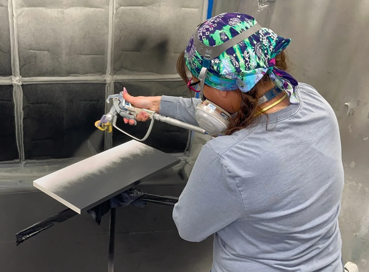 Joyful craftsperson spraying a cabinet finish